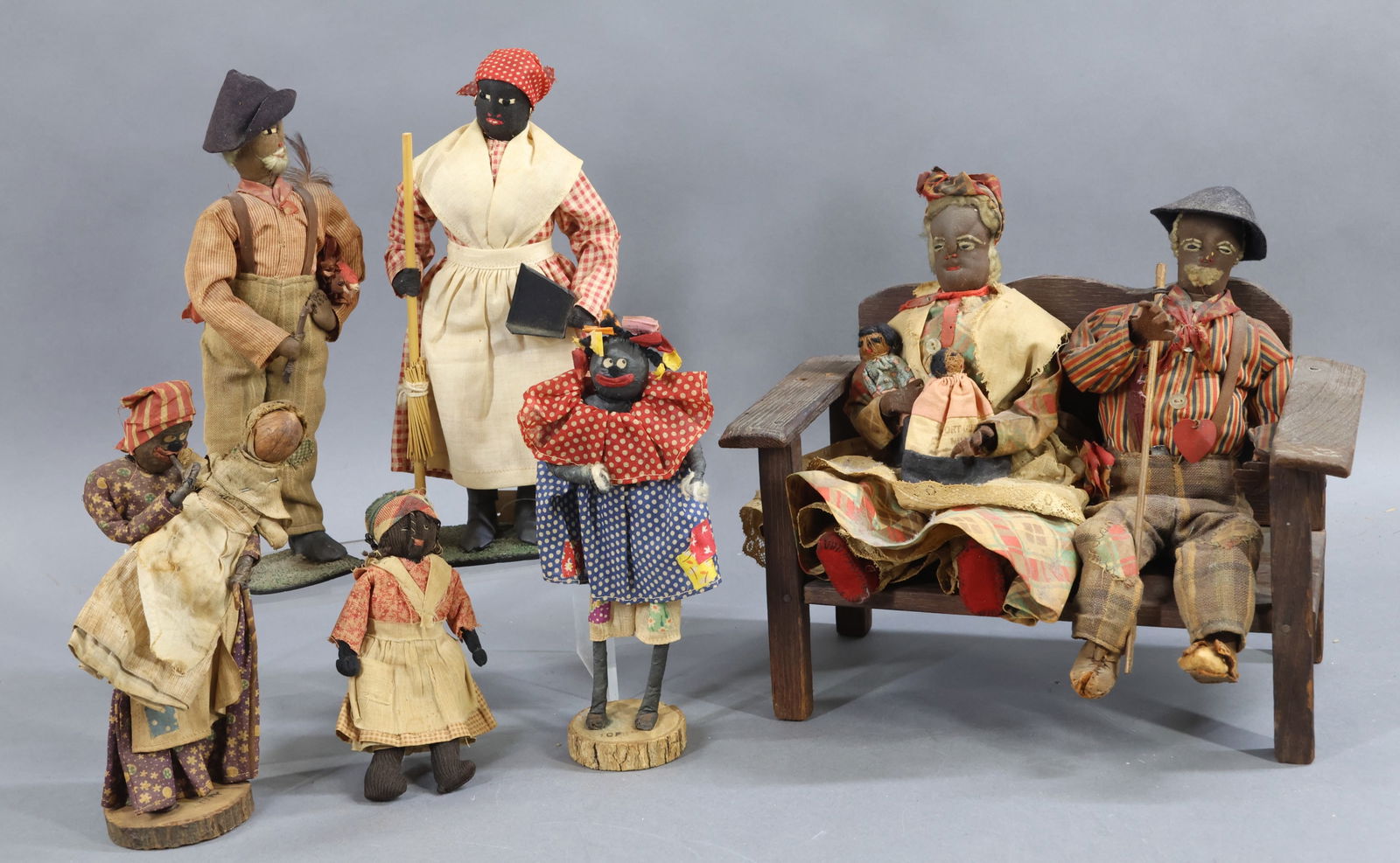 BLACK DOLLS.: LOT of handmade dolls, many from the 1930's. Dolls with cloth heads, embroidered features. Elderly couple sitting on a wooden bench. 9" T x 10 1/2" W x 6 1/4" D. She is holding (2) Seminole Indian