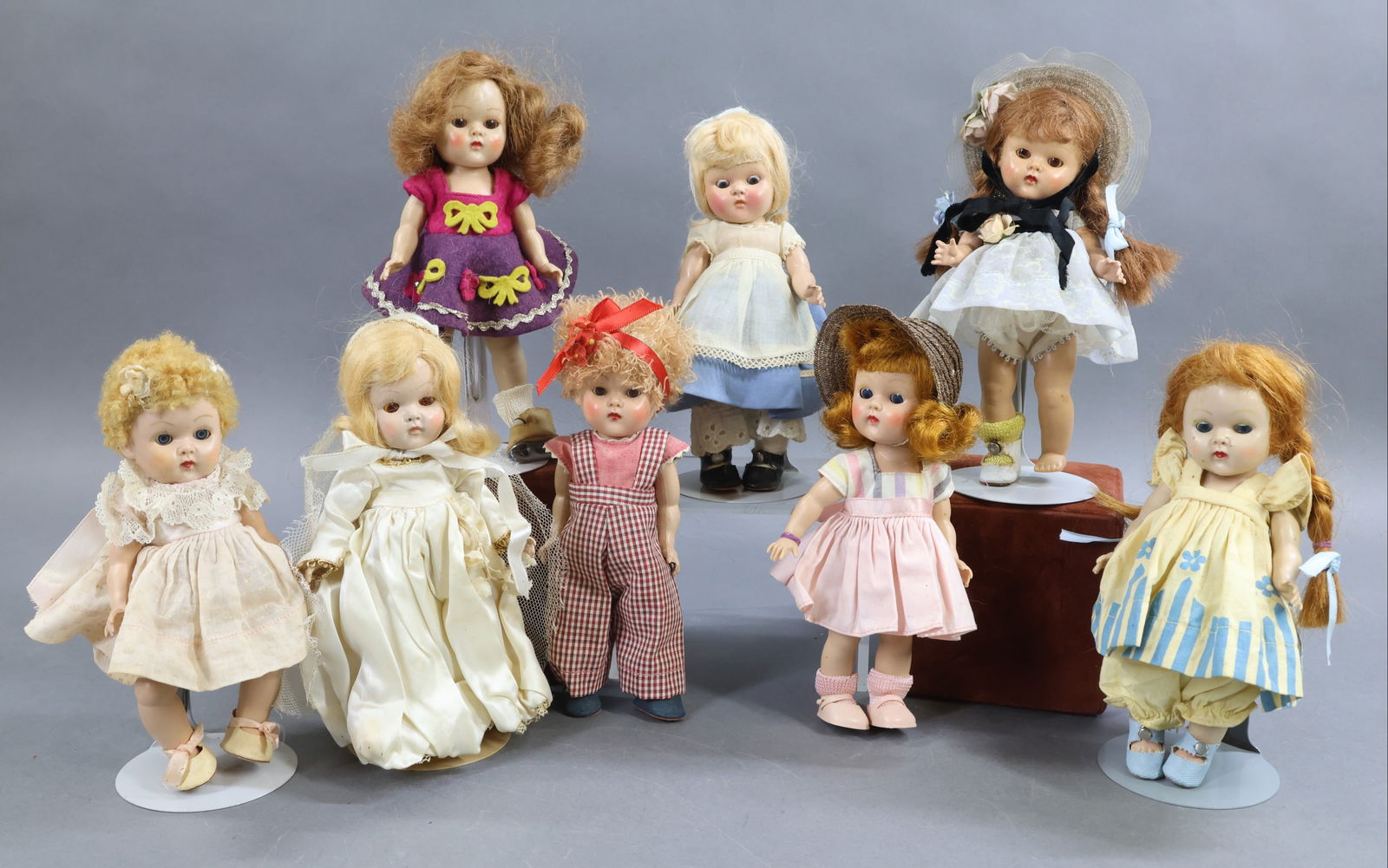 1950's-1960's DOLLS.: LOT of (8) 8" VOGUE "Ginny" dolls. (7) Of them are 1952-1953 and PL SL strung dolls. (1) Is a Baby with PL and strung, wearing a caracul wig. (1) Doll has a replaced wig and wearing a tagged 1940's ou