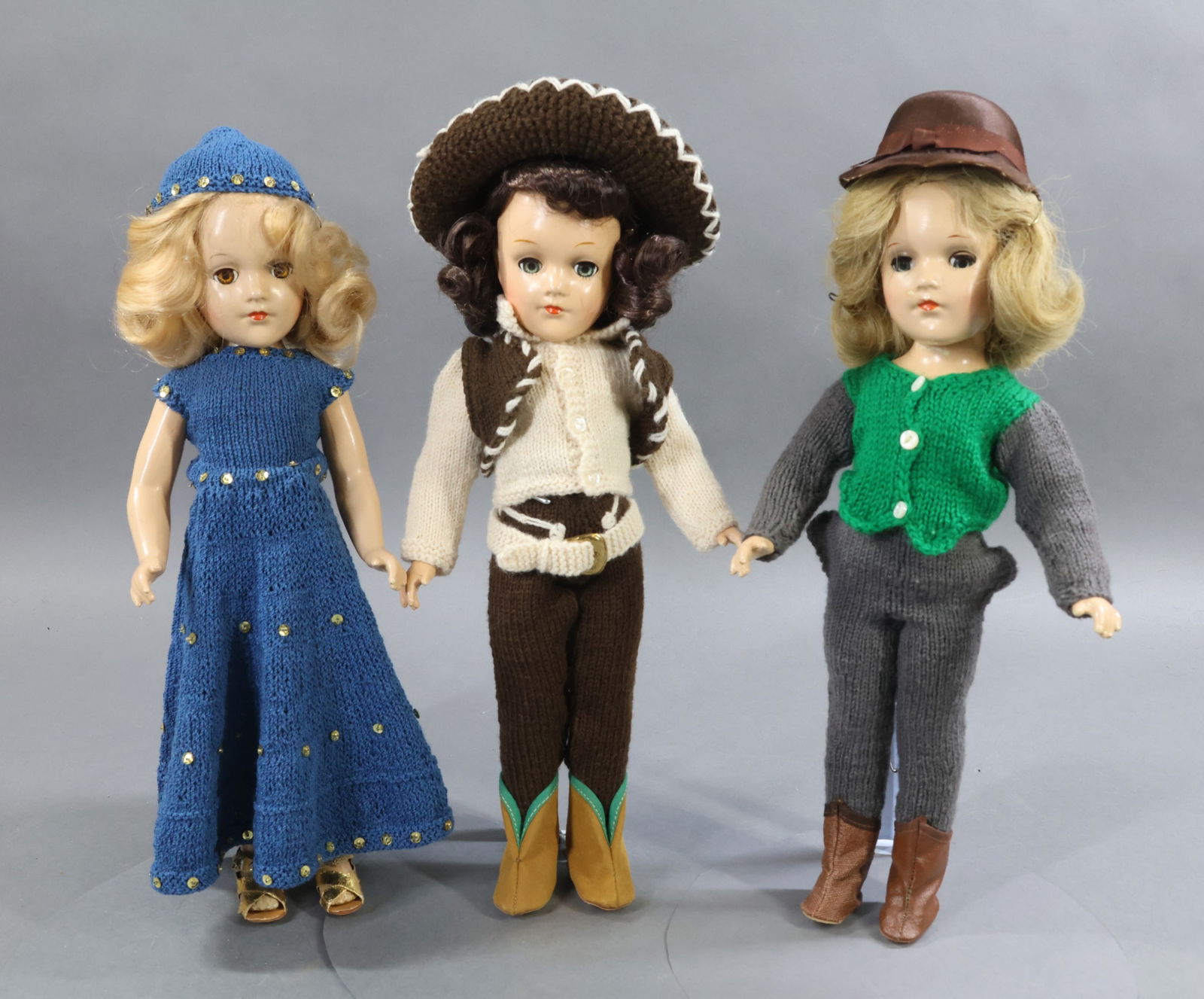 1940's-1960's DOLLS.: LOT of (3) 14" composition MARY HOYER dolls. They are all dressed in outfits knit from the Mary Hoyer patterns. Doll 1) "The Westerner" with dark brown wig, blue sleep eyes. Brown suede boots with spu