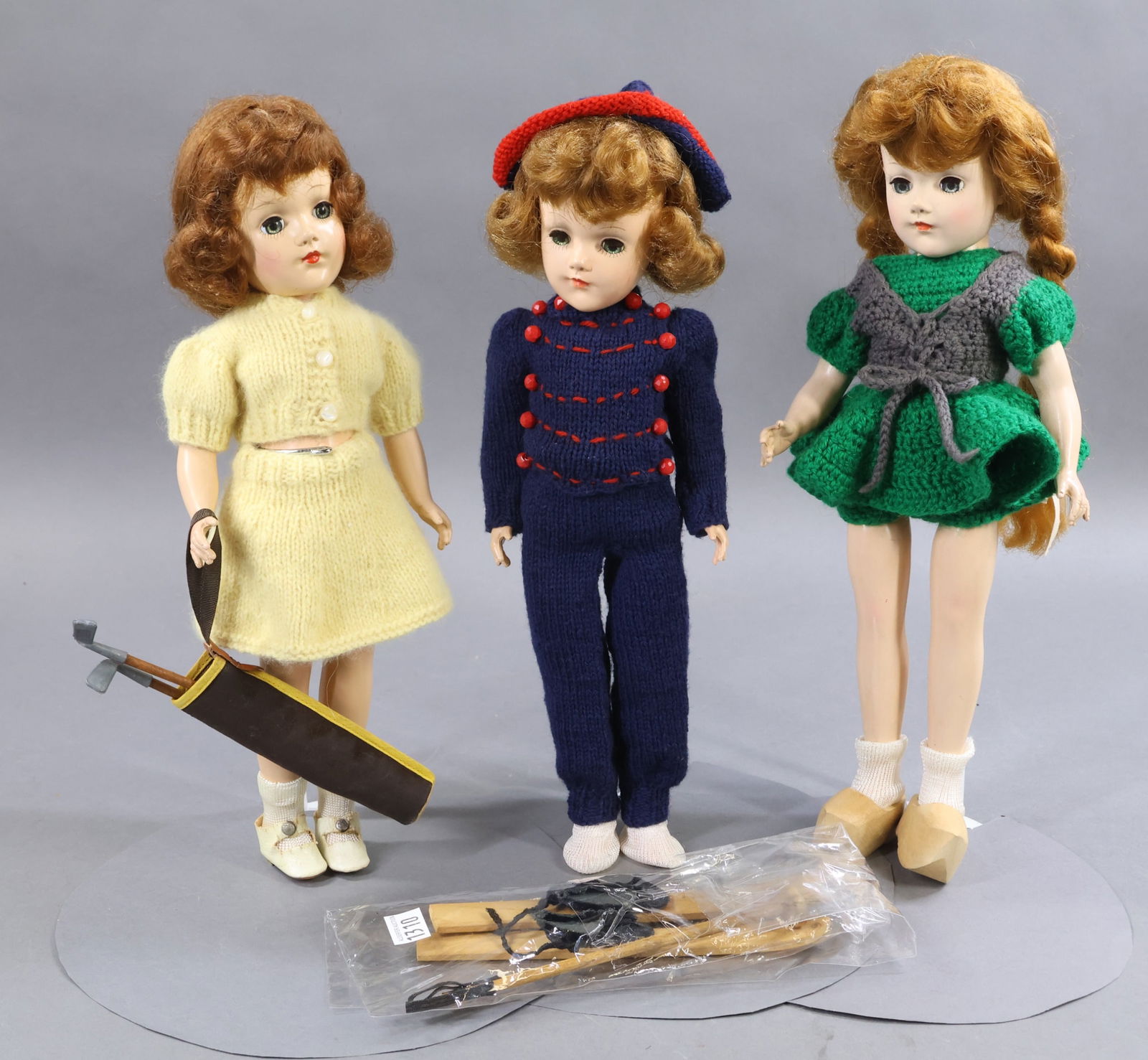 1950's-1960's DOLLS.: LOT of (3) 14" hard plastic MARY HOYER dolls. They are all dressed in outfits knit from the Mary Hoyer patterns. They all have red wigs and blue sleep eyes. (3) Stands. Doll 1) "Sport Suit" (Golfer) w