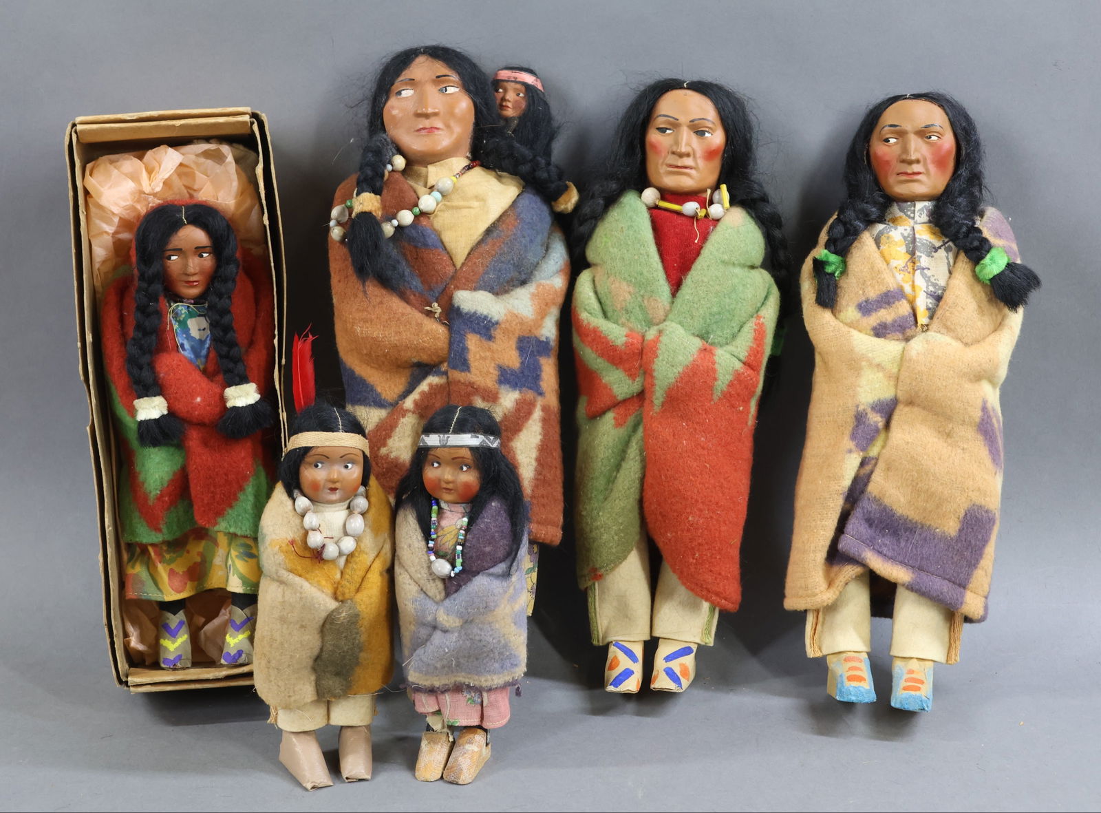 NATIVE AMERICAN DOLLS.: LOT of (6) all original SKOOKUM dolls. All of these dolls have mohair wigs, masking tape moccasins. Pair of 6 1/2" children. (1) Has moccasins, the other had moccasins (but they are no longer