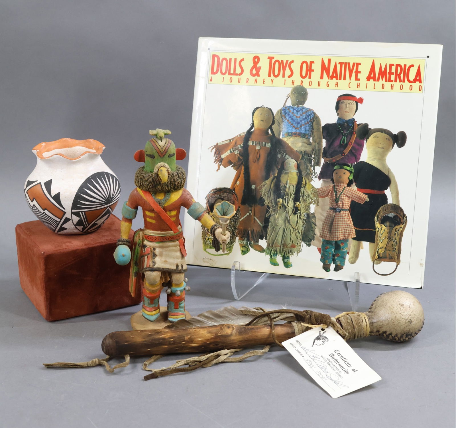 NATIVE AMERICAN DOLLS.: LOT. 8" KACHINA carved wooden doll marked: KYASH "Parrot Kachina", A. Yava 1st Mesa, Hand. 3 1/2" T. Painted earthenware pottery vessel marked R. Juanico Acoma. 12 1/2' Ceremonial Rattle. Wooden