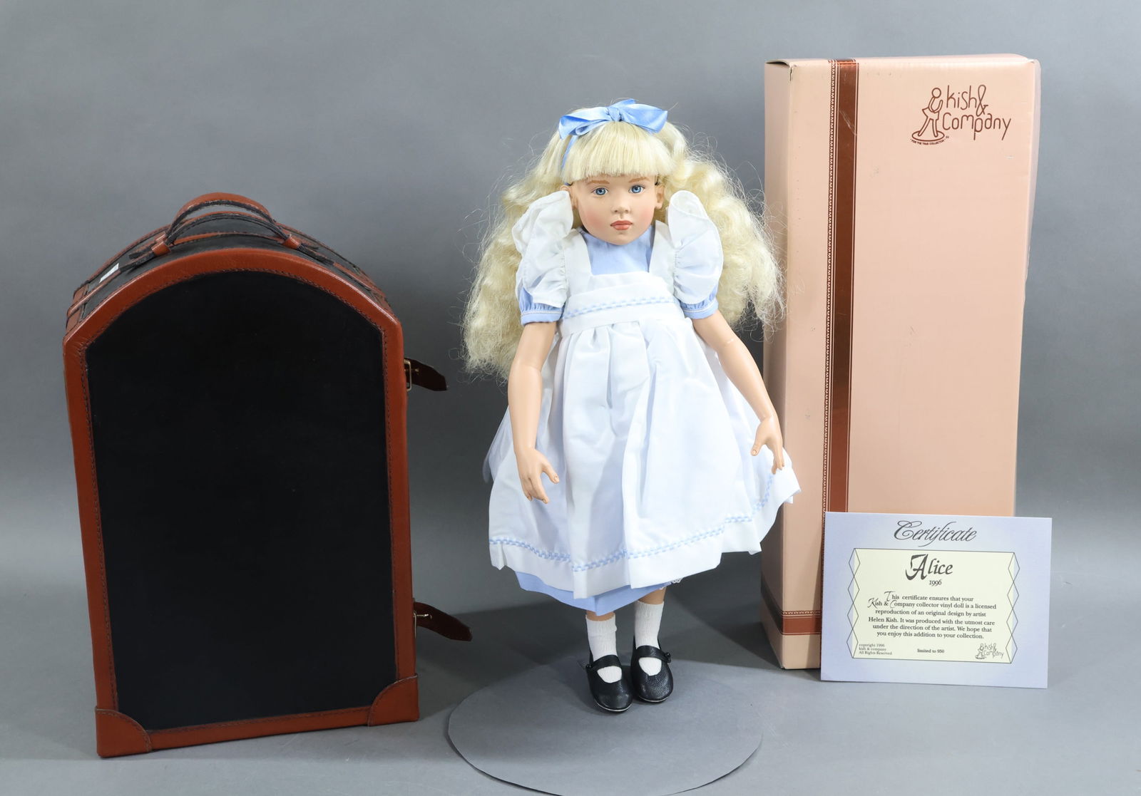 CONTEMPORARY ARTIST DOLLS.: Pair of dolls by artist Helen Kish. MIB 1996 "Alice", No. 628/950. COA. MINT 1993 10" "Cara" and her 13" Trunk. (2) Additional outfits and accessories. This lot is being sold AS IS.