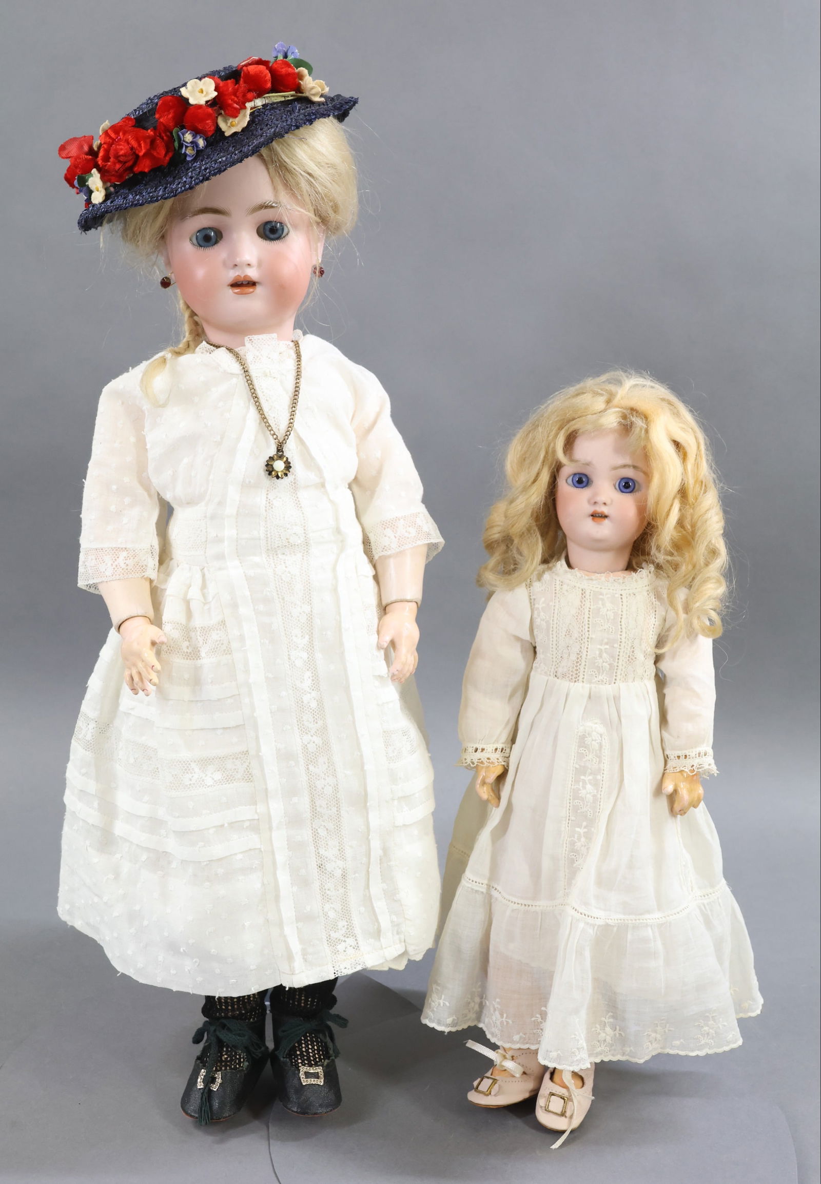 GERMAN BISQUE DOLLS.: Pair of SIMON HALBIG dolls. Both dolls have blue eyes, open mouths, pierced ears, blonde mohair wigs, papier mache jointed bodies. They are dressed in antique white cotton clothing. Doll 1) 13" SH