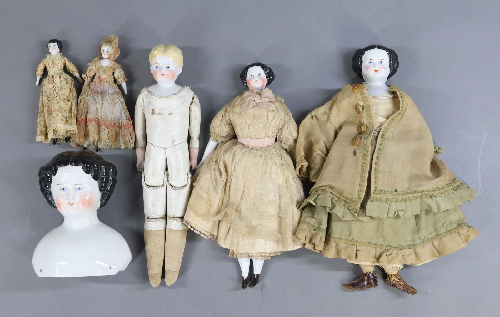 PARIAN/CHINA DOLLS.: LOT. (5) Antique dolls with china shoulder heads and a single shoulder head. Dolls - all of them that are dressed are wearing antique clothing. They have blue eyes. Pair of Low Brows - 6". 6 1/4" (Mar