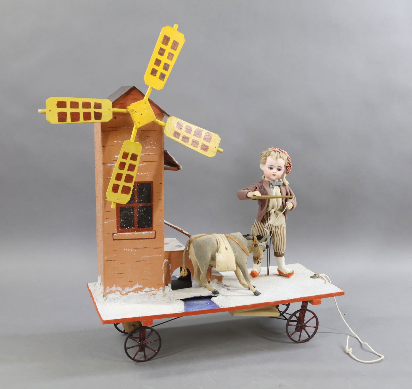 TOYS - ANTIQUE.: Antique Platform Pull Toy. 9" (Horseshoe Symbol) German bisque head doll with stationary blue eyes, open mouth, short curly honey blonde mohair wig. Wire armature body with wooden lower arms, papier