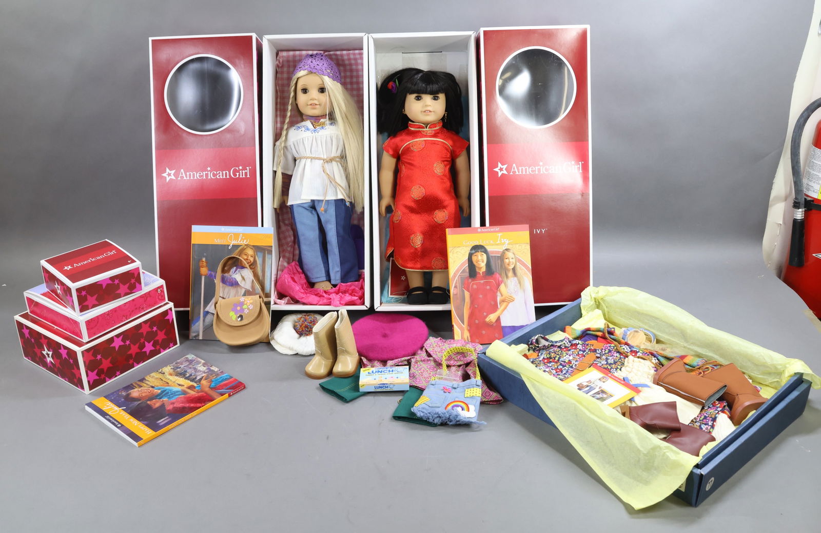 AMERICAN GIRLS.: LOT of JULIE and IVY. Each doll is in OB w/book. Julie comes with additional book. (2) Boxes of mixed Clothing and Accessories for these dolls. Travel Luggage. Condition: outfits may not be complete.