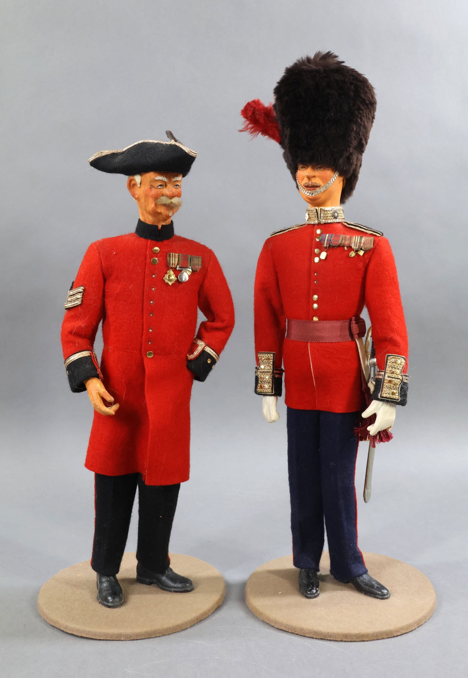 ENGLISH DOLLS.: Pair of men in uniforms. Both men have detailed composite? heads with painted features. Cloth bodies, composite hands, feet. Red & black wool felt uniforms. Both marked Made in England on bottom of