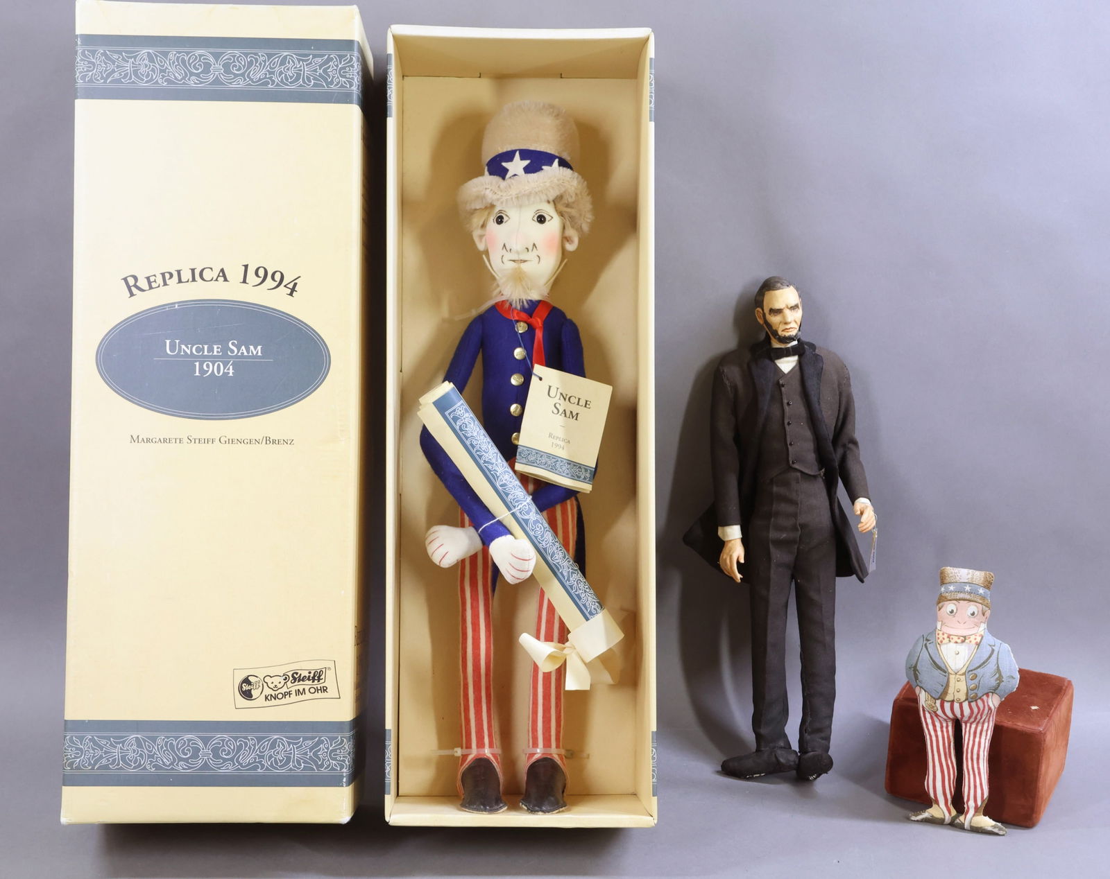 POLITICAL THEME DOLLS.: LOT of (3) dolls. MIB NRFB 20" Replica 1994 STEIFF 1904 "Uncle Sam" doll. Ltd. Ed. 288/1000. 15" Tagged B. RAVCA "Abraham Lincoln" doll. 7 1/2" Antique printed cloth "Brownie" doll marked: