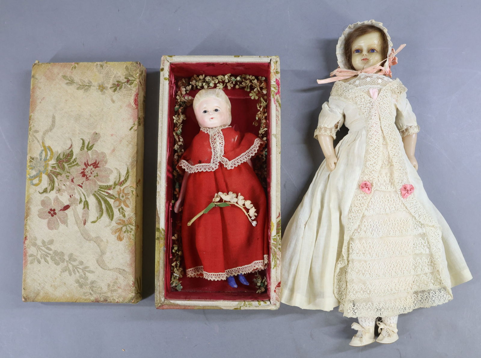 WAX/WAX OVER PAPIER MACHE DOLLS.: Pair of dolls. Wax over - 1) 8 1/2" doll with stationary pupil-less black eyes, closed mouth, molded blonde hair. Cloth body with wooden lower limbs, painted blue boots. Dressed in antique red wool sk