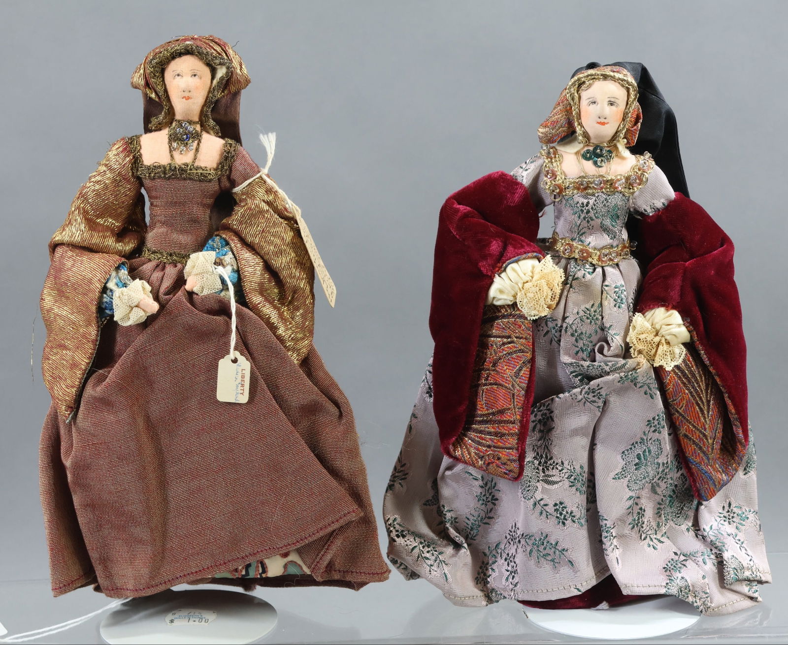 LIBERTY OF LONDON.: Pair of tagged "Kathryn of Aragon" dolls - First wife of King Henry VIII whom he divorced. This Spanish Princess failed to produce a male heir. They are dressed in different outfits. (2) Stands. Condi
