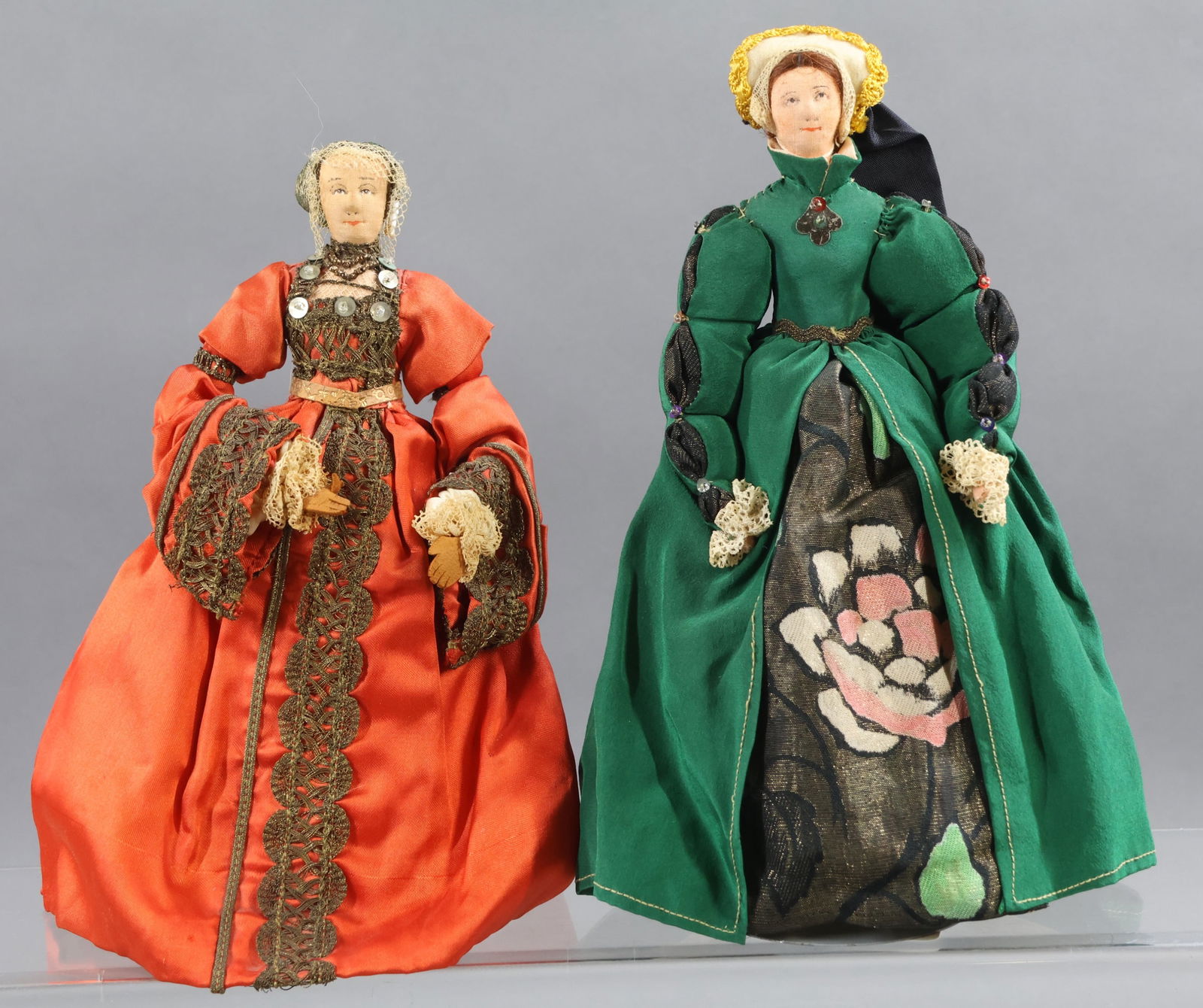 LIBERTY OF LONDON.: Pair of tagged "Catherine Howard" dolls - 5th wife of King Henry VIII. She was beheaded after a short period of time as Queen. They are dressed in different outfits. (2) Stands. Condition: age discolo