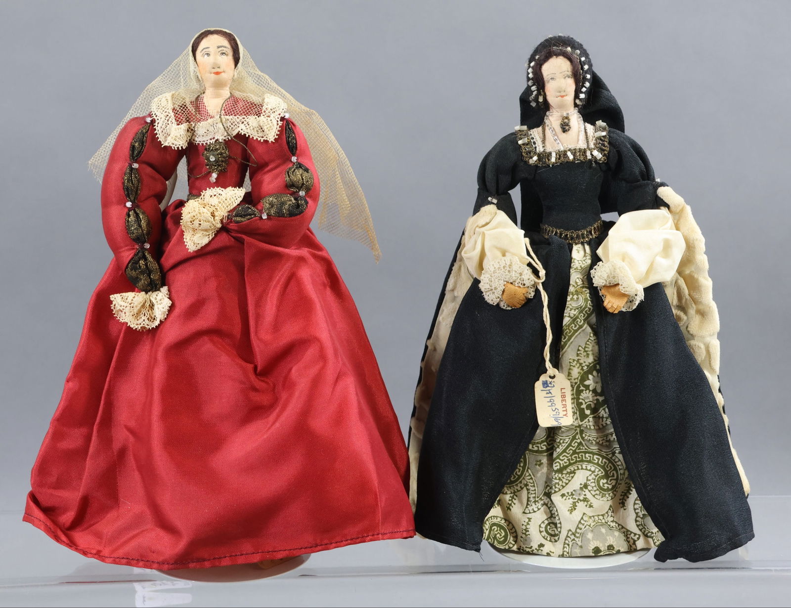 LIBERTY OF LONDON.: Pair of tagged dolls. "Anne Boleyn" - 2nd wife of Henry VIII. (Black gown.) "Katherine Parr" , last wife of Henry VIII. (Red gown.) She cared for him in his old age and sickness and was a good stepmot