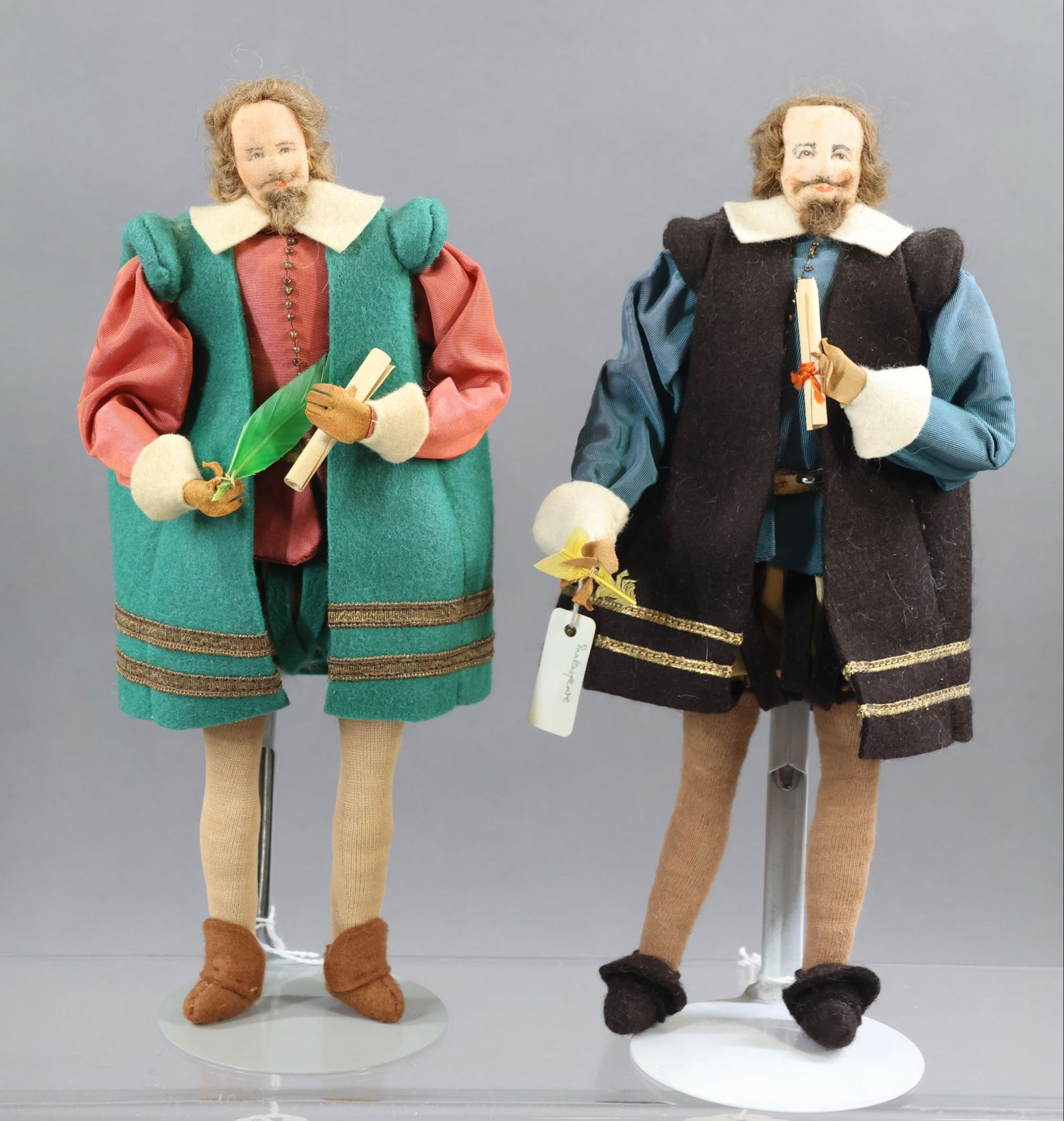 LIBERTY OF LONDON.: Pair of tagged male "William Shakespeare" dolls. One is dressed in green felt, the other in brown felt. (2) Stands. Condition: minor age fading. This lot is being sold AS IS.