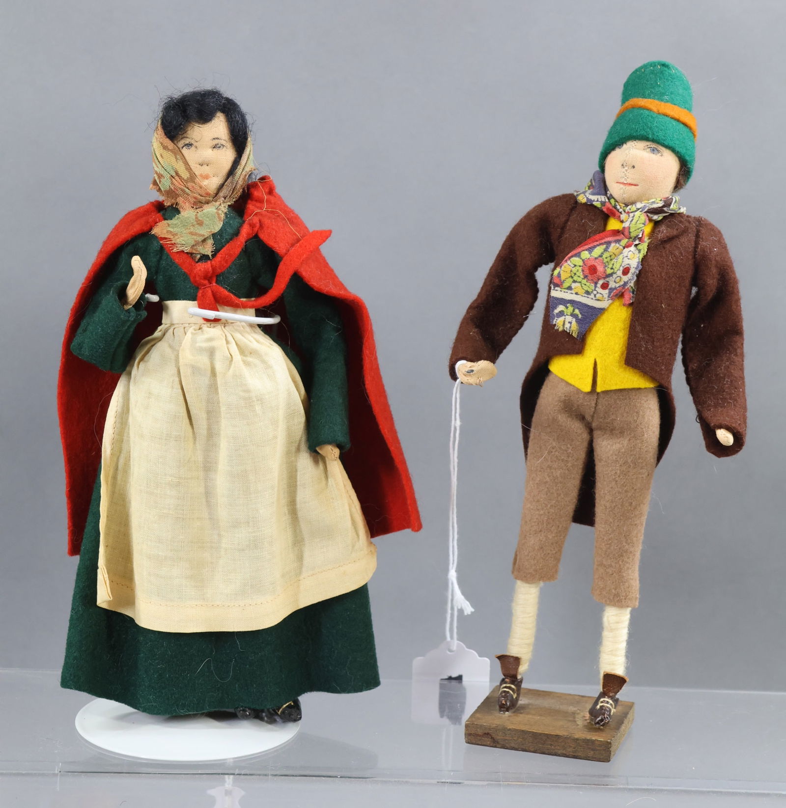 LIBERTY OF LONDON.: Pair of dolls. 9" Unmarked "Early Irish Man". Center seam. He stands on a wooden base. 8" Tagged "Irish Lady". (1) Stand. Condition: nothing observed. This lot is being sold AS IS.