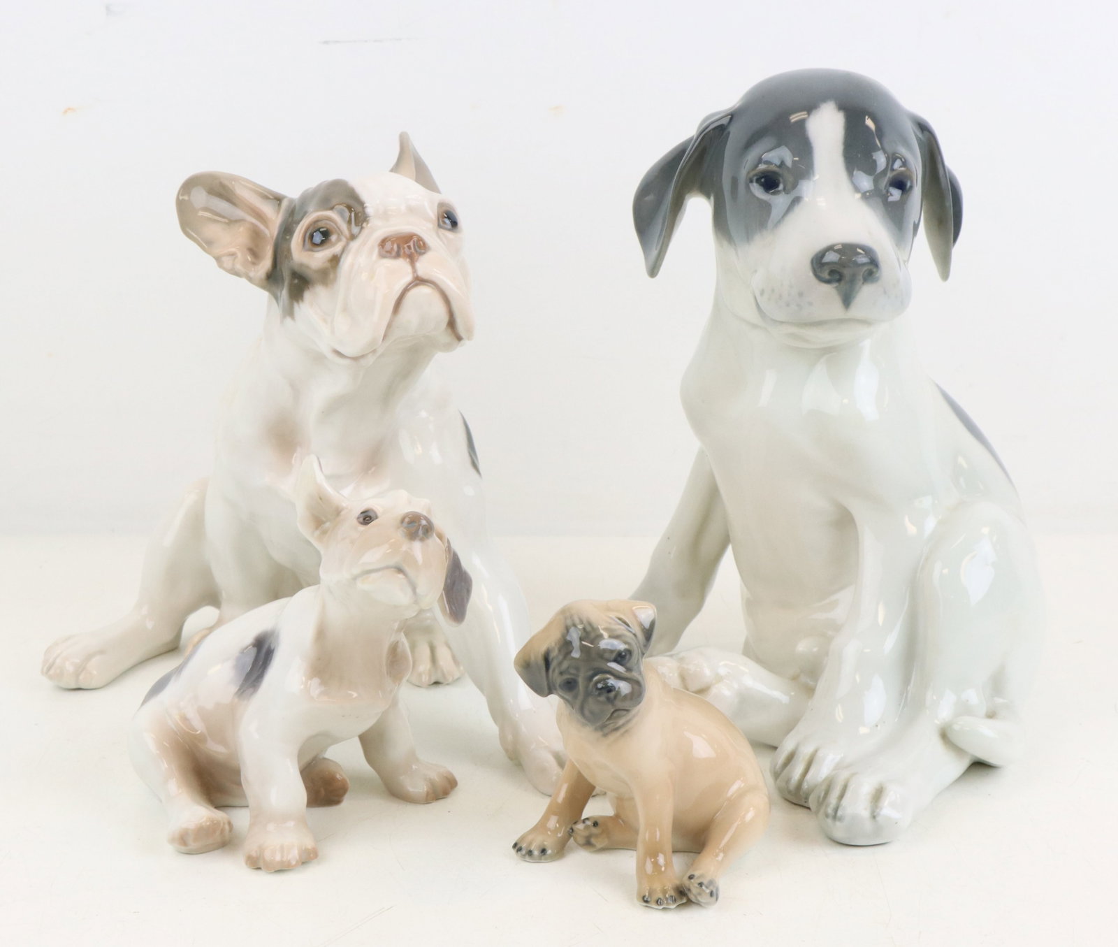 Royal Copenhagen Porcelain Dog Figures: Royal Copenhagen porcelain dog figures (4), includes French Bull Dog, French Bull Dog Puppy, Pug, and a Jack Russell Terrier, all marked. Largest 8”h x 7”w x 5.5”d