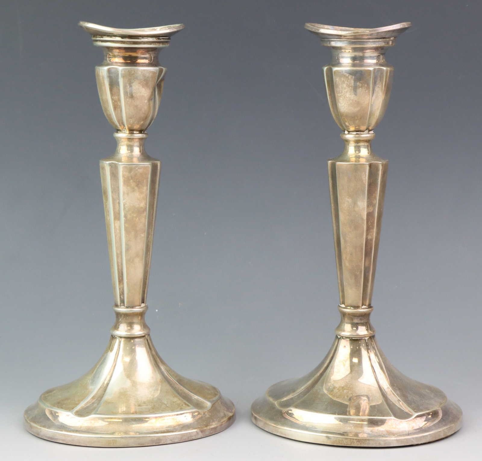 Hans Jensen Danish Silver Candlesticks: Danish 830 silver pair of weighted candlesticks with fluting. Both show the "three towers" 1954 mark, and makers marks for Hans Jensen. One nozzle is dented. (2) pieces. 7.75”h x 4”w x 3.5