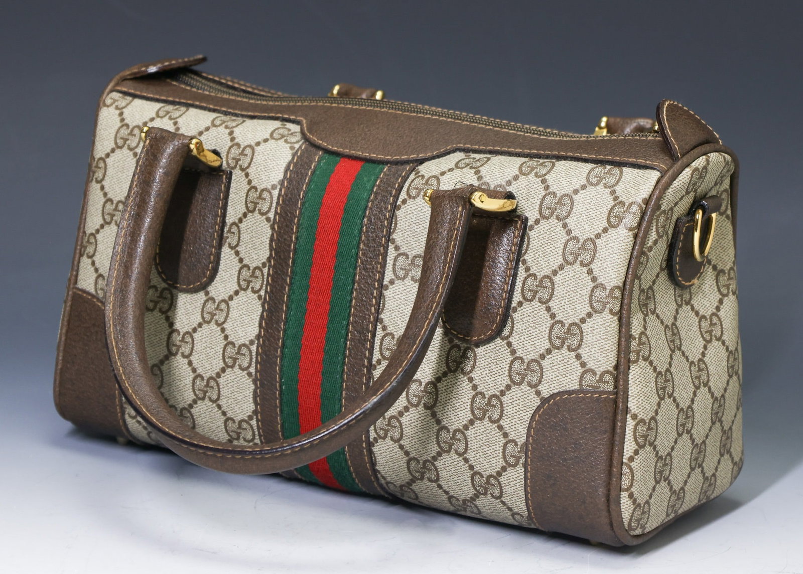 Vintage Gucci Monogram Handbag: GG Monogram coated canvas with leather trim, handles and detachable cross body strap, interior zipper pocket, stamped logo on hardware, distinct wide web stripe and rests on four small metal feet.