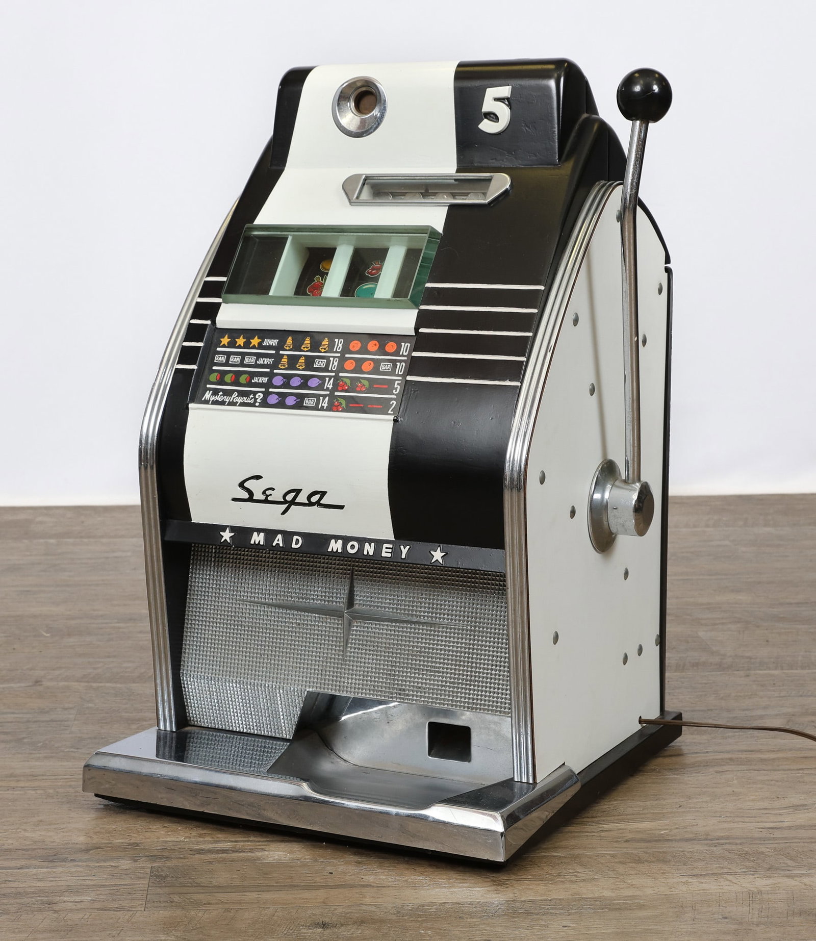 Sega Mad Money Slot Machine: Sega Mad Money slot machine, mid 20th century, countertop with painted metal cabinet in black and white with chrome trim, mechanical lever operation, painted payout chart, coin mechanism missing rear