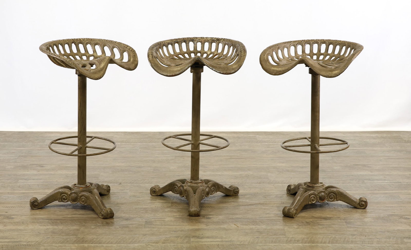 Baker & Hamilton Tractor Seat Stools: Cast iron with swivel saddle seats, leg rest, with scrolled tripod bases. Marked, "Baker & Hamilton, San Francisco, Sacremento" on seat. 31"h x 18.5"w x 16"d
