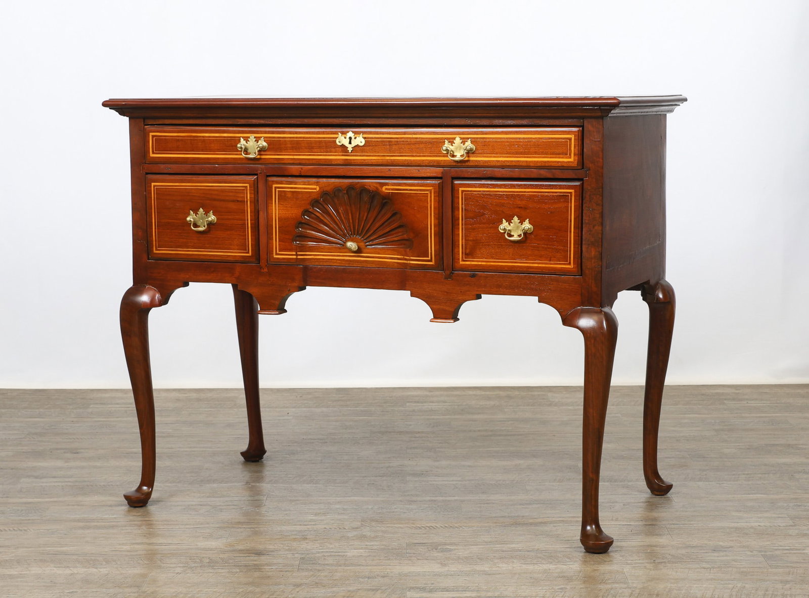 Mahogany and Inlaid Lowboy: Rectangular chamfered top, one over three dovetail and banded inlaid drawers with the center drawer having a shell carved motif, shaped apron, on cabriole legs and pad feet. One back leg has been repa