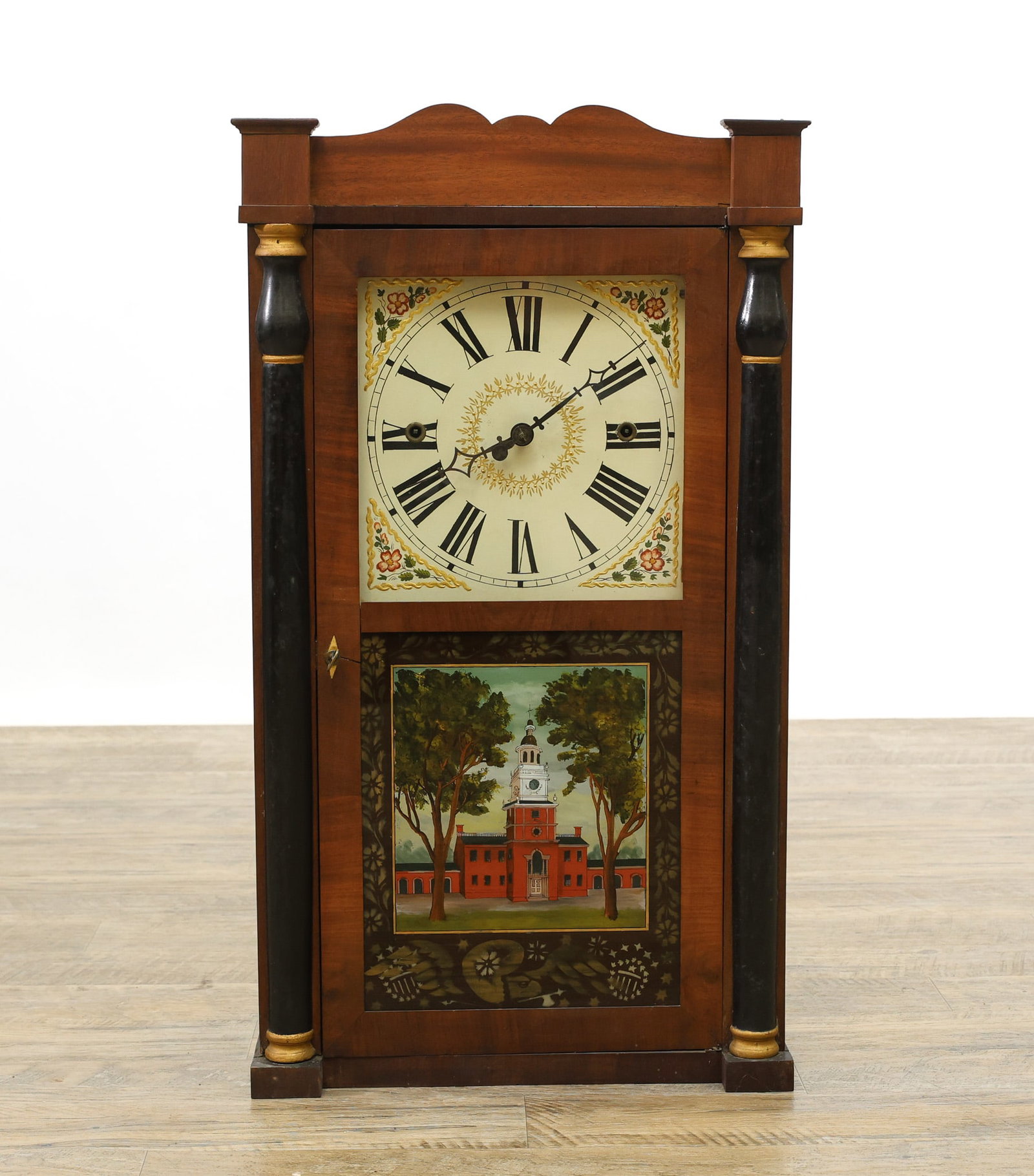 Norris North Connecticut Shelf Clock: Mahogany case with a scrolled top single door with eglomise tablet of Independence Halldoor flanked by gilt accent and ebonized columns on a plinth base. Eight-day movement with a painted and