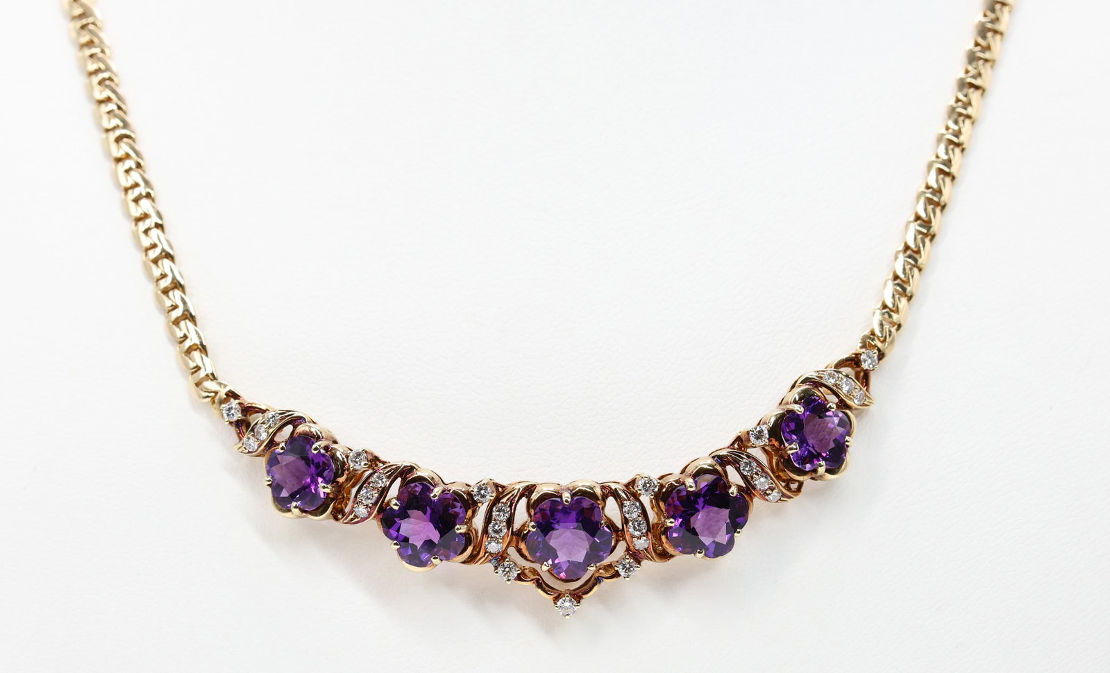 14k Amethyst Diamond Necklace: 14k yellow gold necklace set with five flower form amethysts totaling approximately 9.00 carats and (27) round brilliant diamonds totaling approximately .56 carat, SI1 clarity, 17", 12.9dwt.