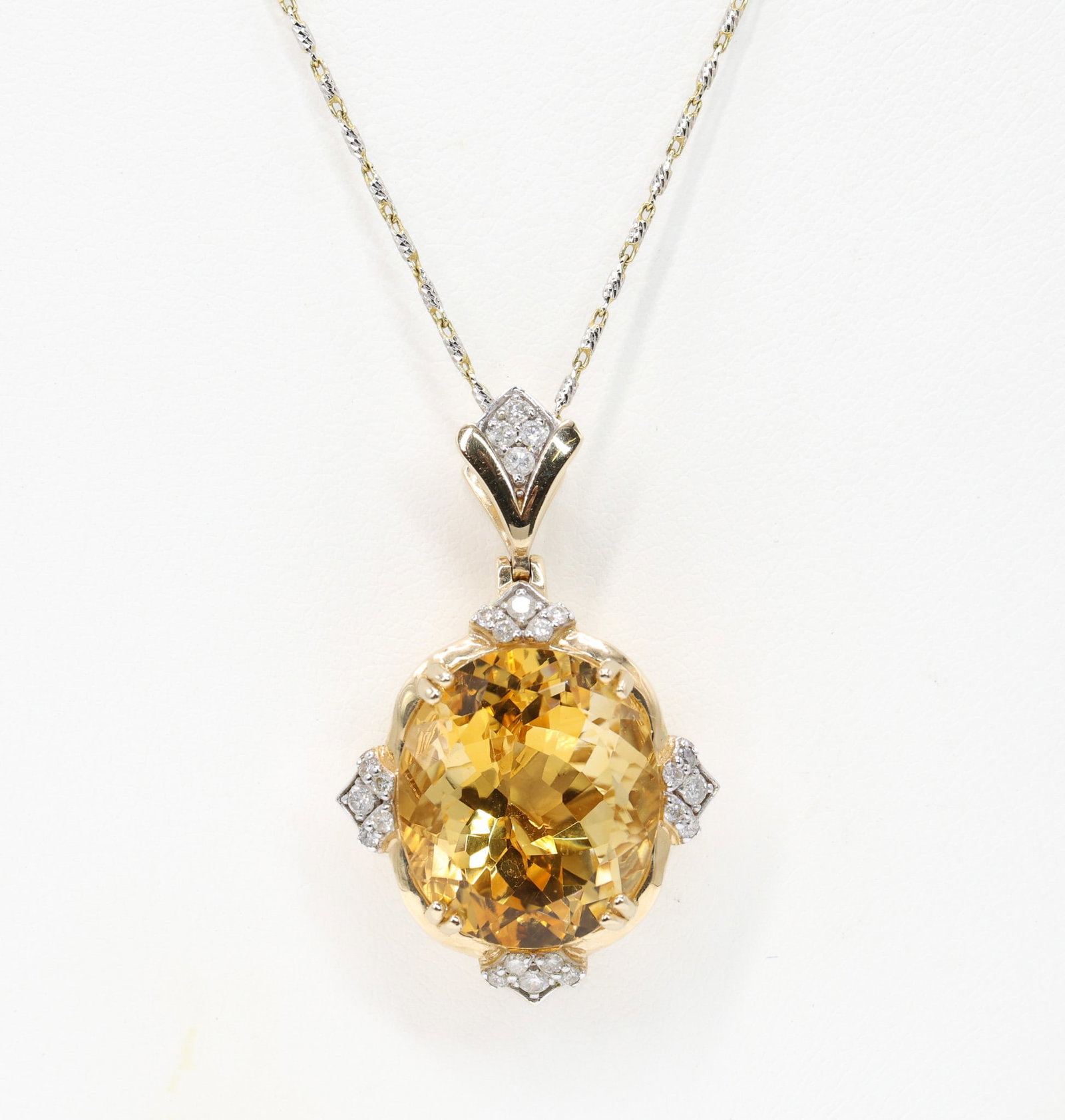 14k YG Citrine Necklace: 14k two tone gold pendant necklace set with a natural oval brilliant cut citrine quartz weighing 15.15 carats, orangey yellow in color with intense saturation and transparent clarity, within a round