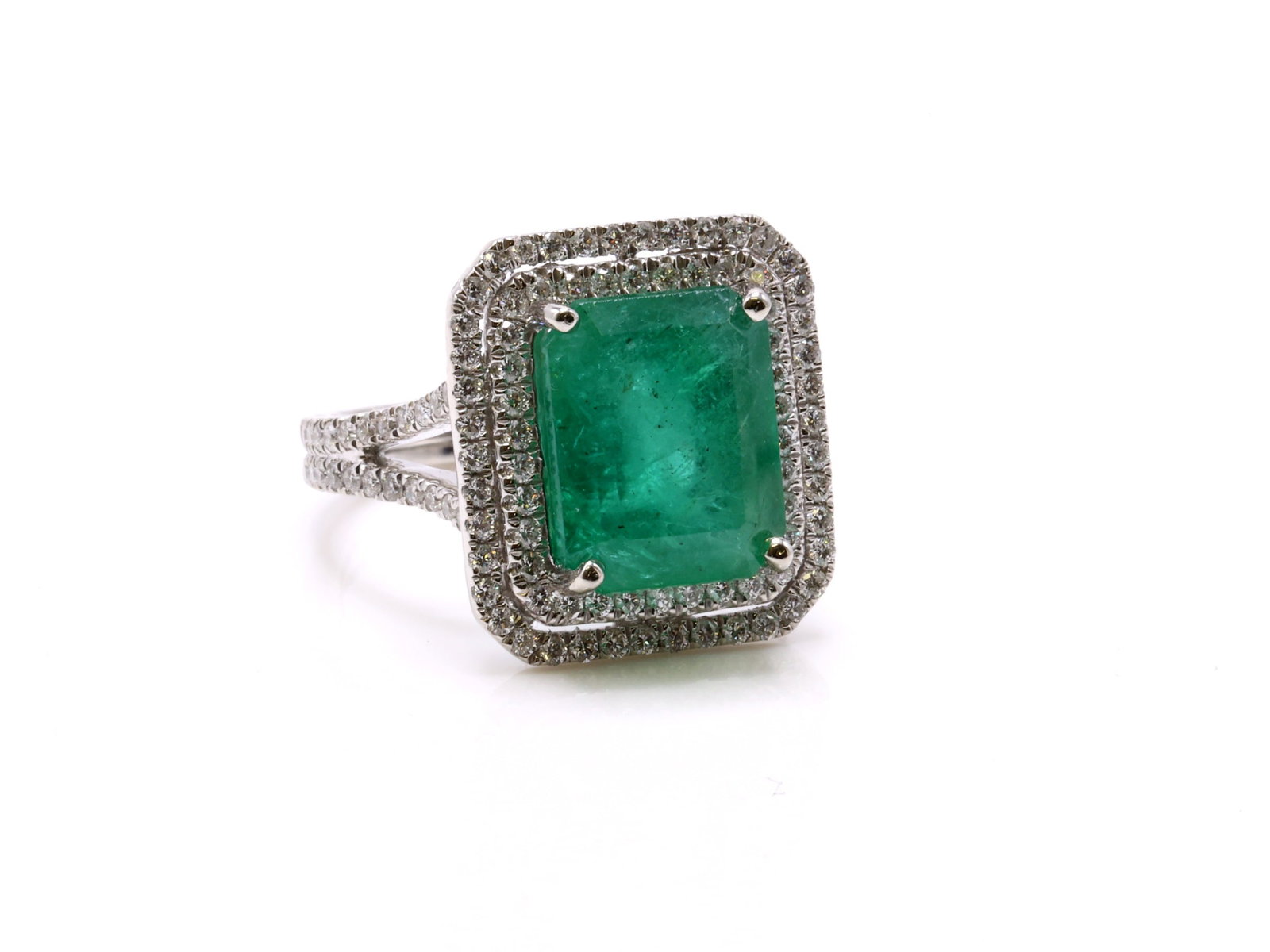 Platinum Emerald Diamond Ring: Platinum ring set with an octagonal step cut natural emerald weighing 6.48 carats in a double halo setting with split shank, accented by (144) round cut diamonds totaling 1.03cttw. AIGL appraisal repo
