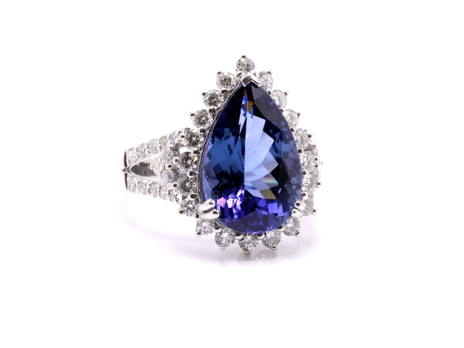Platinum Tanzanite Diamond Ring: Platinum ring set with a natural pear modified brilliant cut tanzanite weighing 6.47 carats, violet blue in color with intense saturation and transparent clarity, accented by round brilliant cut