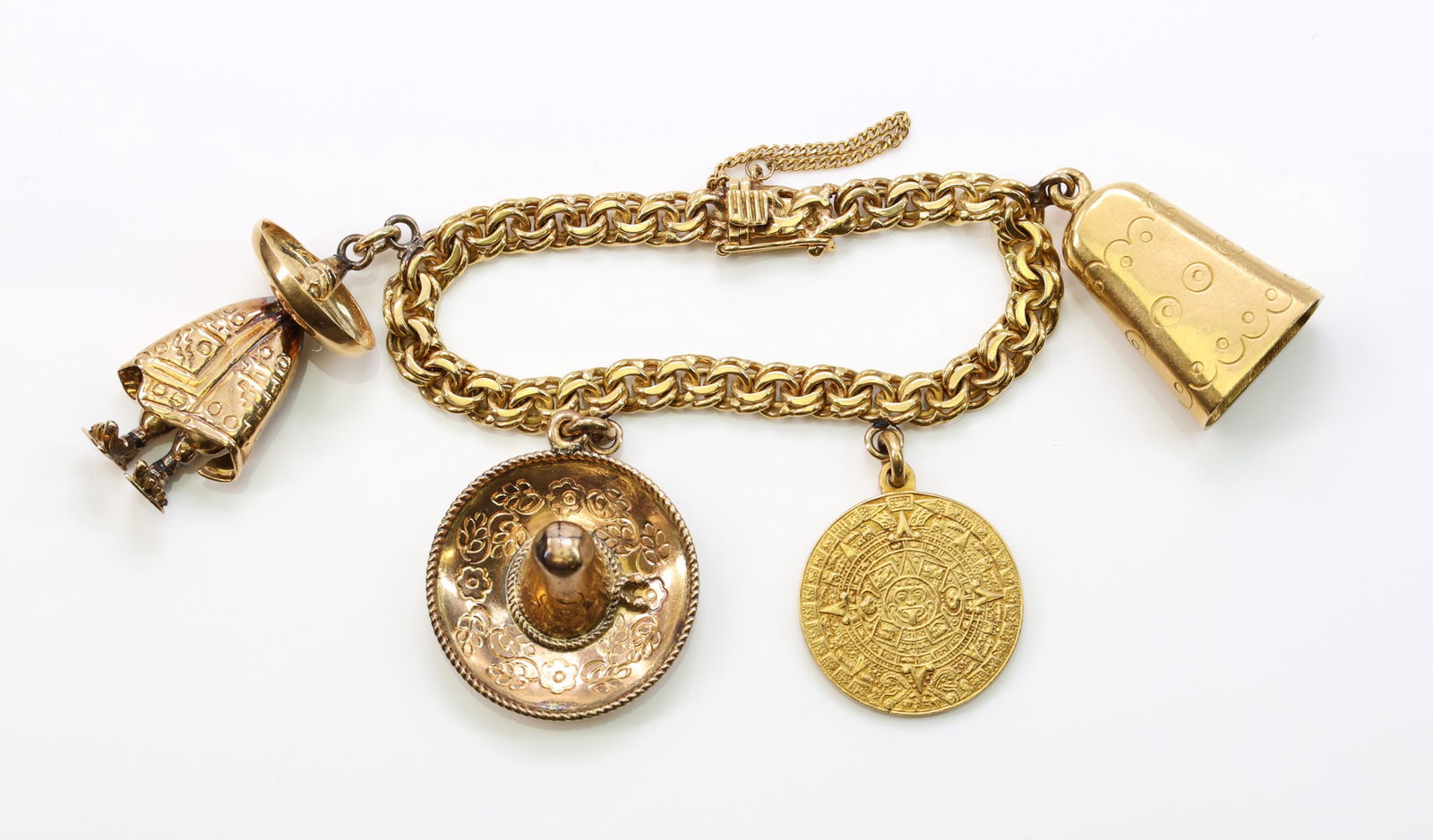 18k YG Charm Bracelet: 18k yellow gold charm bracelet with three 18k charms including a figural charm, an Aztec calendar, a bell and one goldfilled charm (sombrero). 6" length. 49.9 dwt.