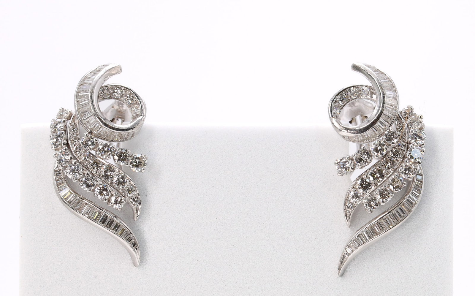 Platinum Diamond Earrings: Platinum earrings set with round and baguette cut diamonds in a scroll design, 6.2dwt.