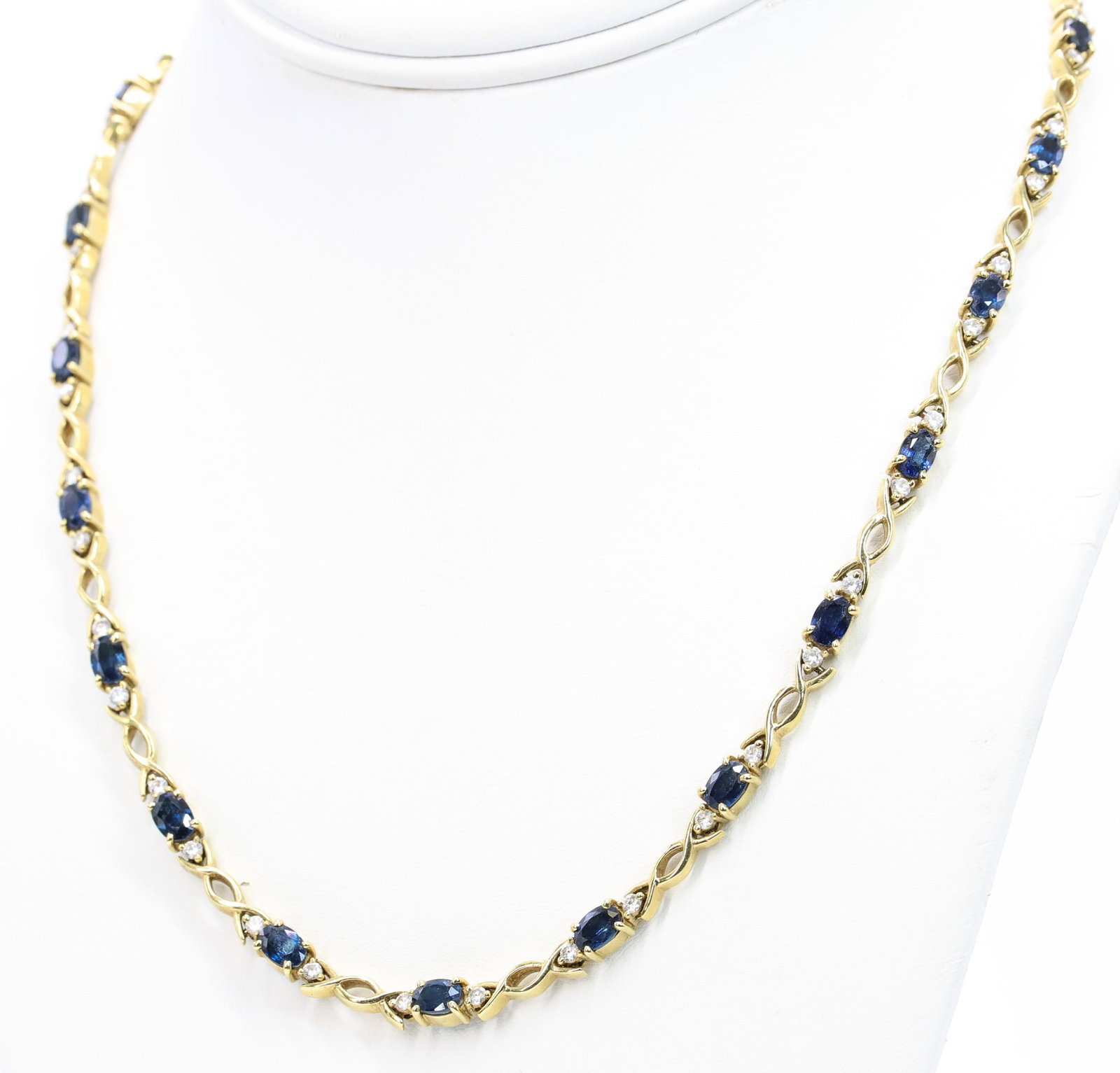 18YG Sapphire Diamond Necklace: 18k yellow gold necklace set with approximately 15 carats of oval cut sapphires and approximately .9 carats total weight round brilliant cut diamond accents in alternating infinity link settings. 18" 