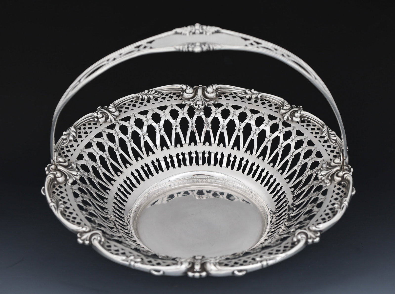 Redlich Sterling Silver Bonbon Basket: American sterling silver bonbon basket with openwork, featuring rosettes and scrolling acanthus decoration and a bail handle. Retailed by Bailey, Banks, and Biddle. First half 20th C. 2"h x 8.75" excl
