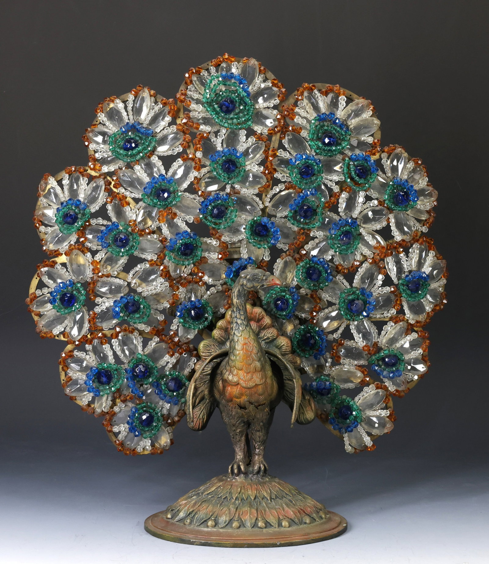 Art Deco Peacock Lamp: Cold painted spelter peacock form lamp with faceted colored and clear glass tail, unmarked, probably Czech. In working condition. There are splits to the metal above the legs, but the piece is