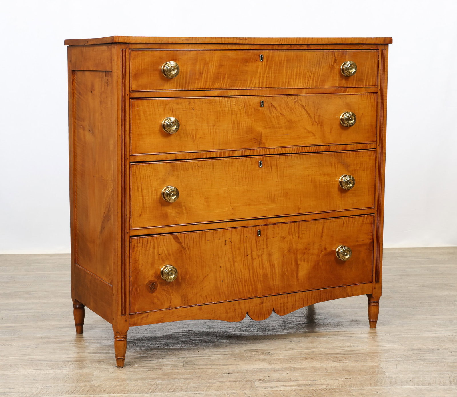 Sheraton Tiger Maple Chest of Drawers: Rectangular overhung top, paneled sides, four graduated drawers flanked by reeded columns, shaped skirt, on turned tapered legs. Pulls have been replaced. 41.5"h x 41.5"w x 19"d
