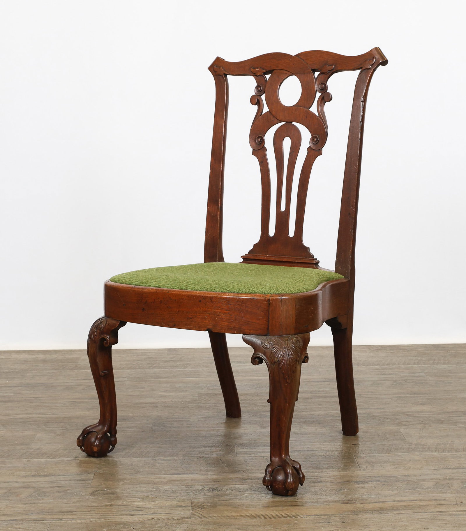 Philadelphia Chippendale Side Chair: Mahogany with a scrolled crest wiith terminating volutes, pierced strapwork splat with double scroll volutes, balloon seat with textured upholstery, acanthus carved knees with volute returns,