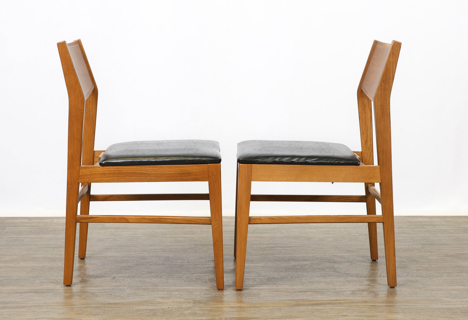 Accent Chairs: Fruitwood side chairs with boomerang stiles, flared tapered square legs, shaped side and back stretchers, and extra wide seats with black vinyl upholstery. Stamp marks under the seats. Some scuffs.