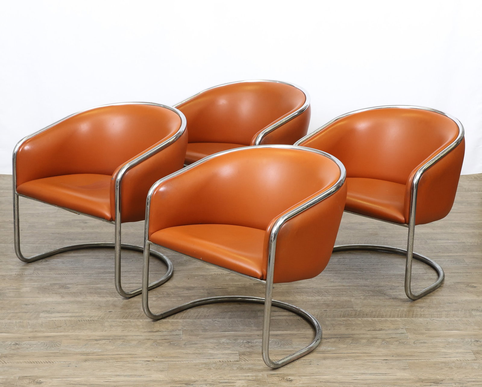 Joan Burgasser for Thonet "Club Tub" Chairs: Cantilever lounge chairs with chrome tubular steel frames and burnt orange vinyl upholstery. Labeled. Surface wear including some scuffs and stains; pitting. A set of (4). 29"h x 28"w x 25"d,