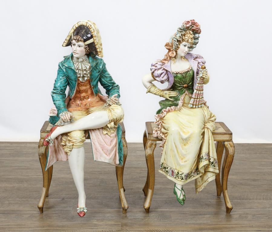 Capodimonte Porcelain Figures: Italian porcelain pair of figures, a courting couple in 18th century attire, sitting on an antiqued parcel-gilt white painted Florentine bench marked Made in Italy. Mid 20th C. The male figure has a