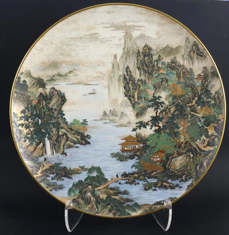 Kinkozan Japanese Satsuma Pottery Charger: Meiji - Taisho era charger depicting a mountain landscape with water, figures engaged in various activities, buildings, and a boat in the distance, with moriage and gilt accents. Impressed Kinkozan ma