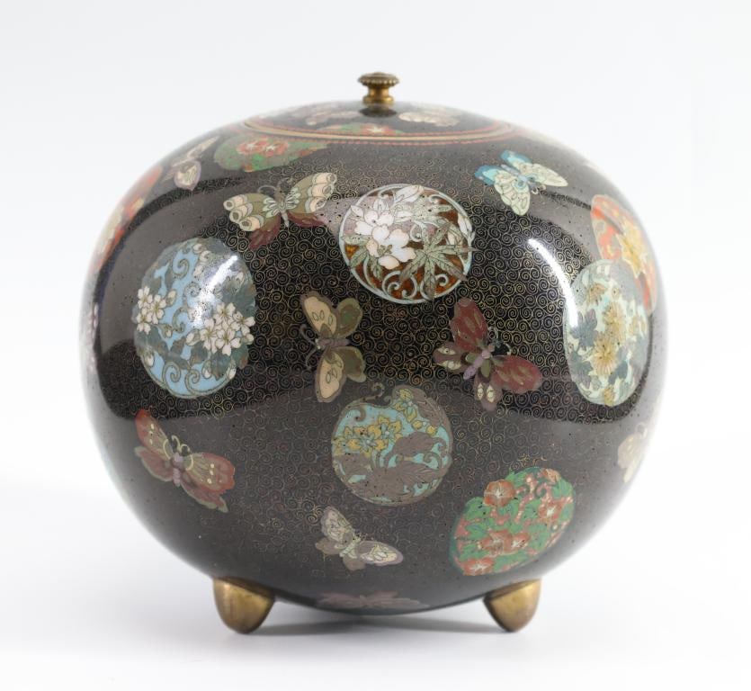 Japanese Cloisonne Jar: Meiji - Taisho era globular cloisonne jar decorated with flower balls and butterflies and featuring fish roe borders on a black ground with wire scrolls, raised on tripod feet. Unmarked. 4.5"h x 4"w