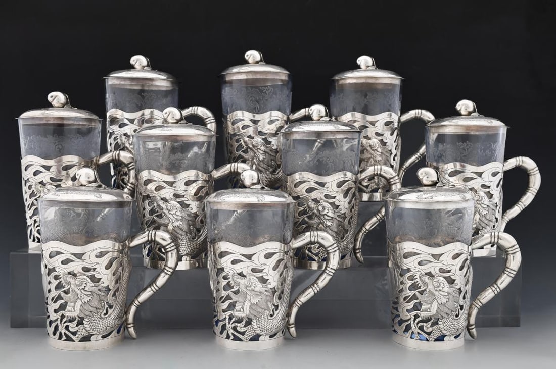 Fang Jiu Xia Chinese Silver Cup Set: Republic era set of cups with openwork, repousse, and chased silver frames and covers decorated with four-clawed dragons chasing flaming pearls, the finials in the form of peaches and the handles in f