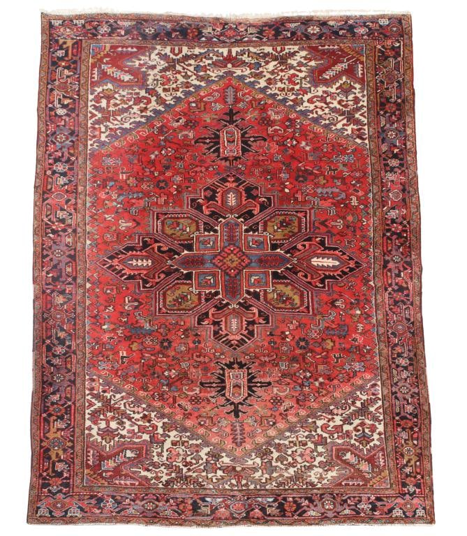 Persian Heriz Carpet: Hand knotted having a central rectilinear and geometric pendant medallion with foliate, stylized flowerhead, and arabesque motif field, meandering stylized flowerhead cartouches in the main border, in