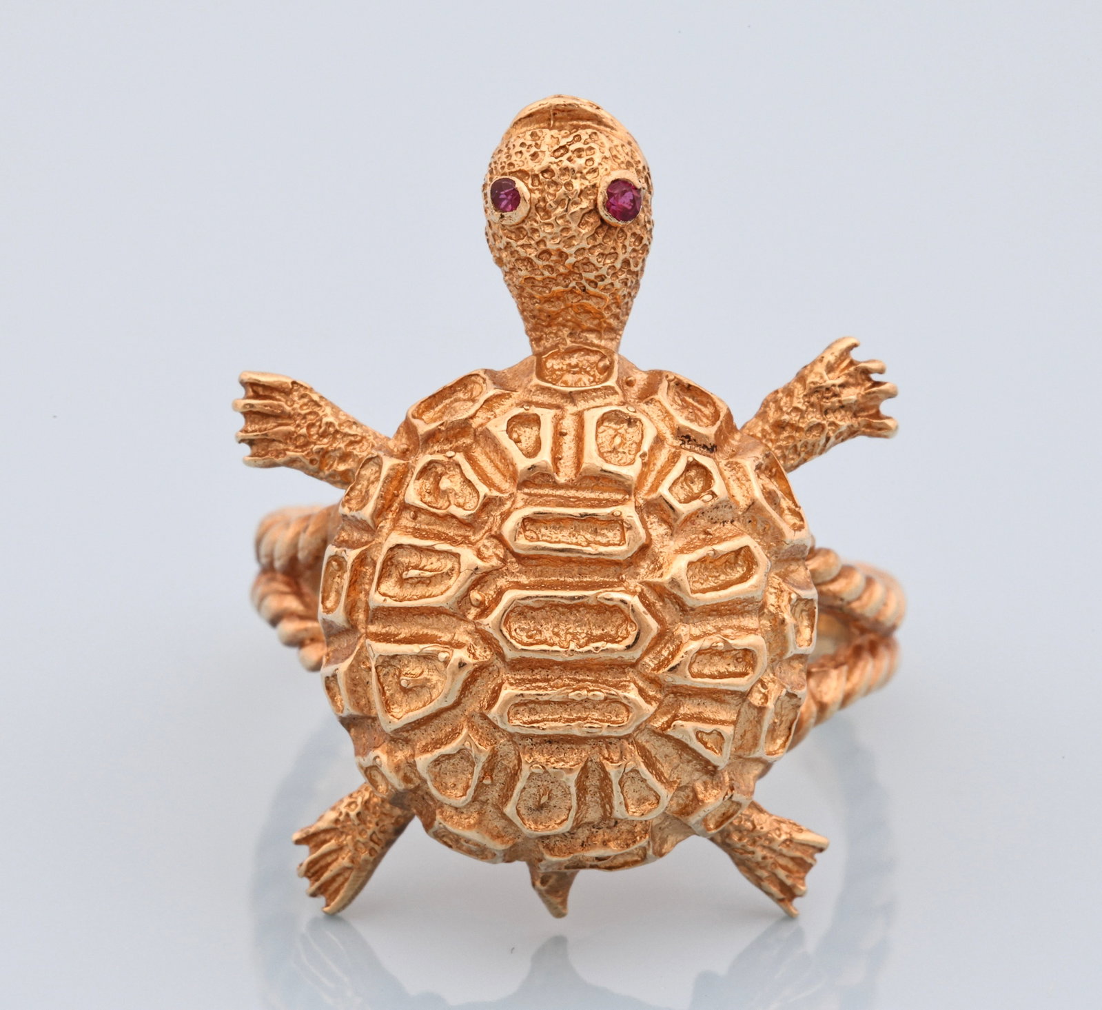 14k YG Ruby Ring: 14K yellow gold figural turtle ring with textured shell and twisted rope-form shank, set with two round ruby eyes. Ring size 7.5. 1"h. 4.5 dwt.