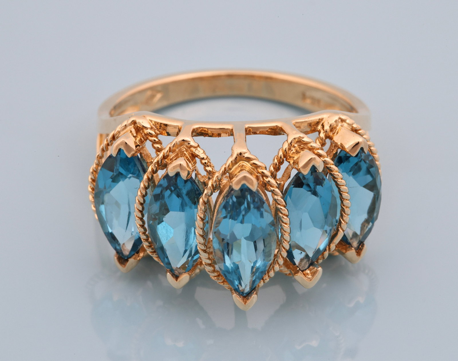 14K YG Blue Topaz Ring: 14K yellow gold ring with five marquise cut Swiss blue topaz gemstones, approx. 4.00 ctw, in openwork settings with rope twist borders. Size 6.25 and 2.5 dwt.