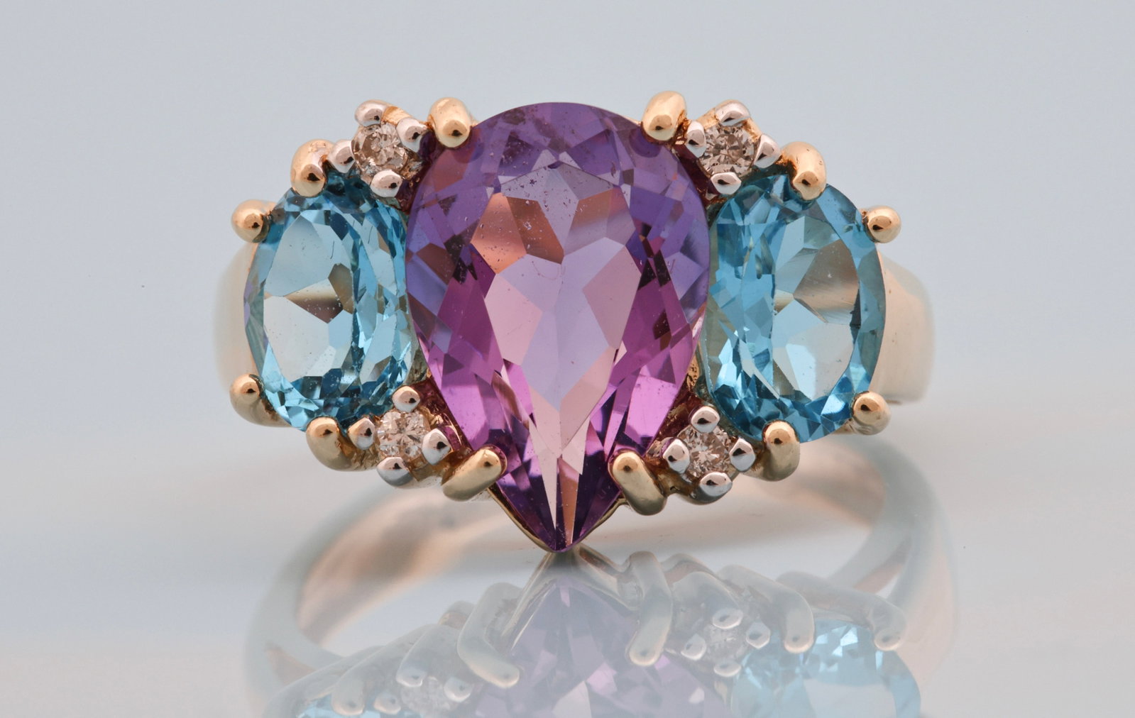 14K YG Amethyst, Blue Topaz & Diamond Ring: 14K yellow gold ring with a pear cut amethyst weighing approx. 2.50 carats, flanked by two oval cut Swiss blue topaz weighing approx. 1.00 carat each, with round brilliant cut diamond accents. Size