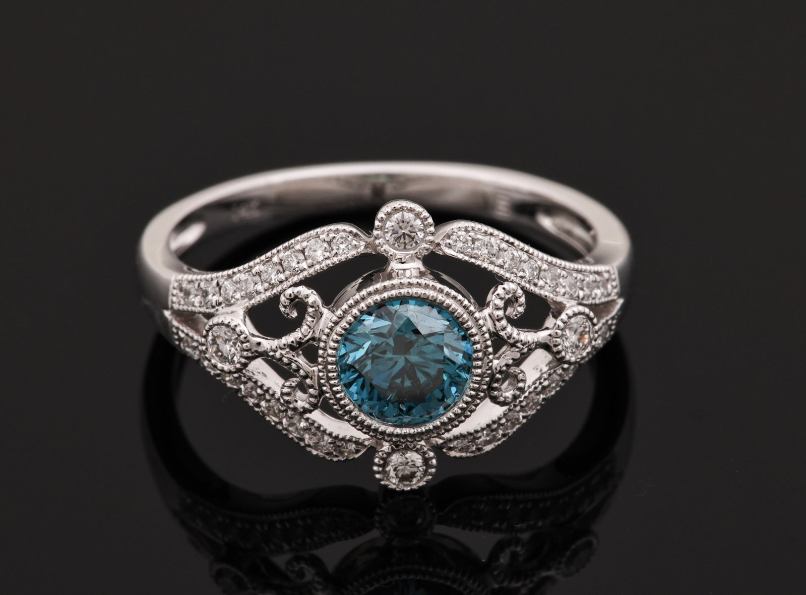 14K WG Blue Diamond Ring: 14K white gold ring with an approx. 0.50-carat round brilliant cut blue diamond and round brilliant cut diamond accents in an openwork setting with milgrain detail. Size 6.25 and 2.1 dwt.