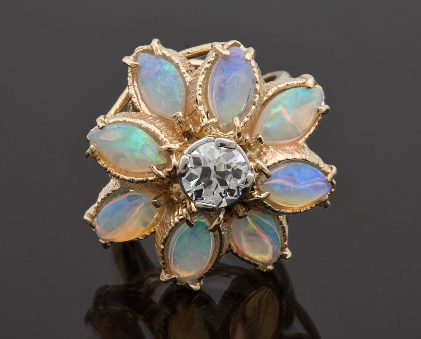 14K YG Opal and Old European Cut Diamond Ring: 14K yellow gold floral cluster ring with a 0.67 carat Old European cut diamond surrounded by eight marquise cabochon opals measuring approx. 8mm long. Ring size 6. Gross weight 4.9 dwt.