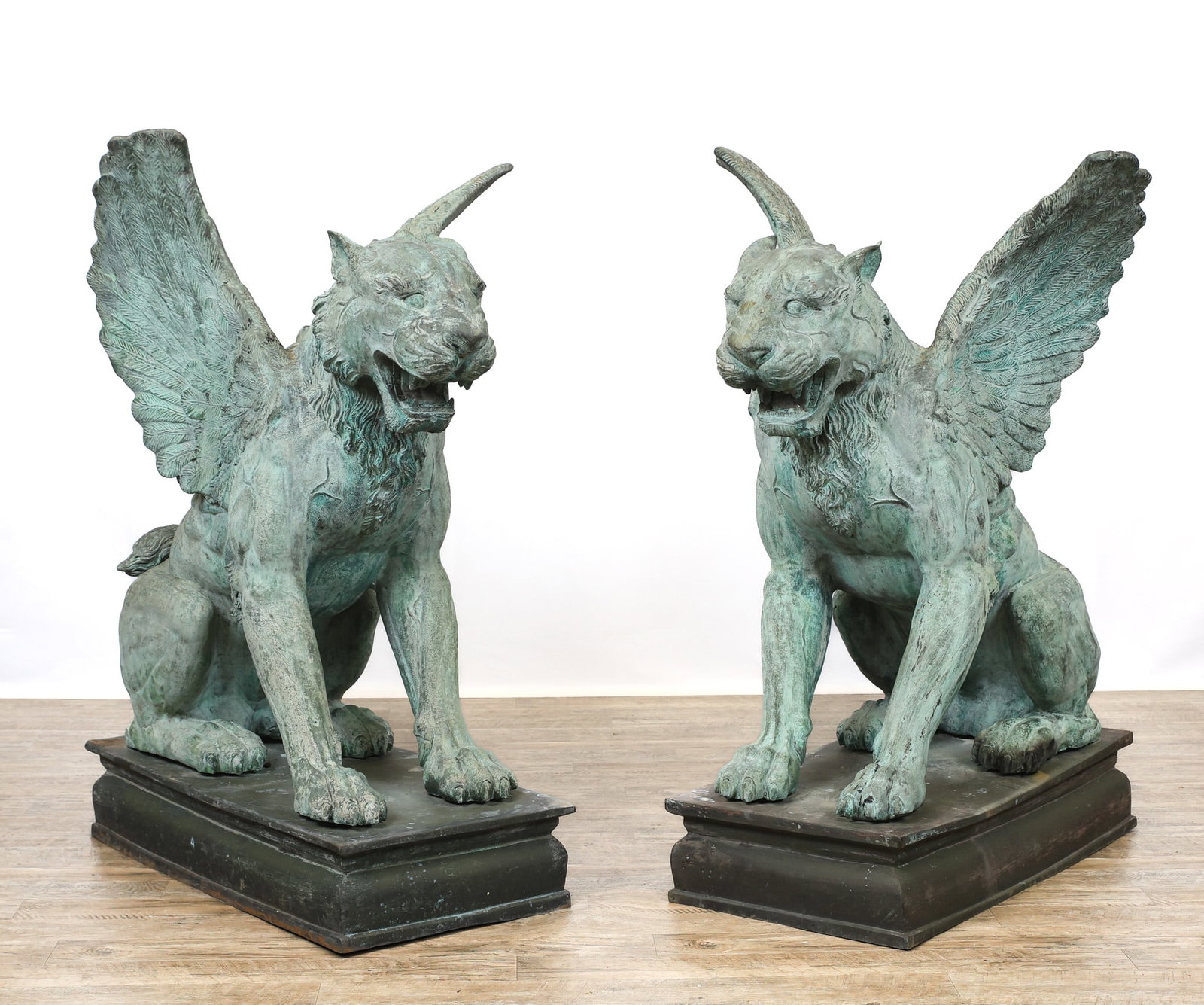 Monumental Patinated Bronze Winged Lion Guardian Statues: Lions seated atop a platform base, unsigned. 49"h x 30"w x 43"d